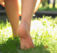 Person walking barefoot on summer grass