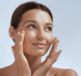A woman with her hands on her face, applying face cream thinking about urea in moisturizers vs. other ingredients