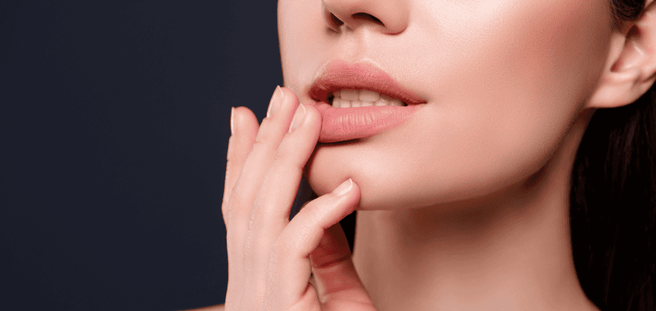 Close up of a woman's face, one hand touching bottom lip applying Manuka Honey Lip Balm