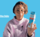 Chloe DeBre holding a packet of Flexitol Very Dry Skin Cream on a blue background